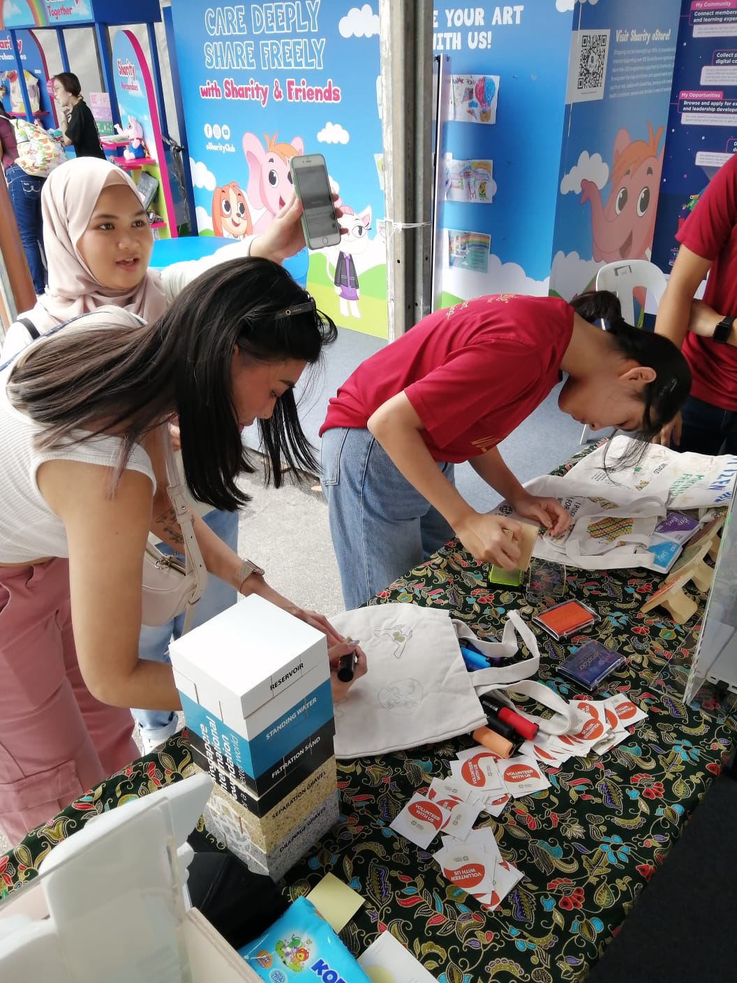 Booth visitors drawing on bags at SIF's booth at Giving Week
